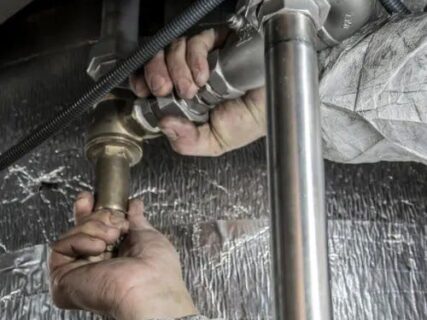 Pair of hands holding connecting water pipes together.