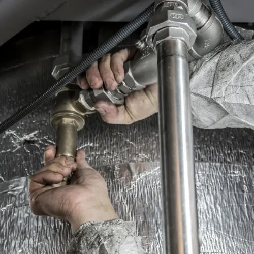 Pair of hands holding connecting water pipes together.
