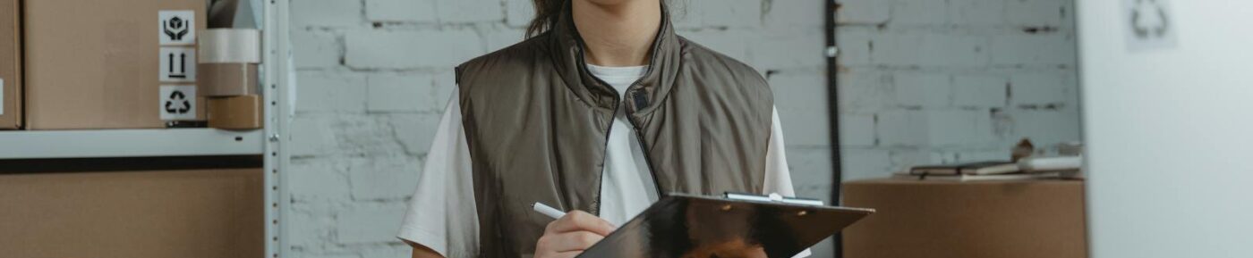 Young woman with clipboard in a warehouse, managing inventory with precision.
