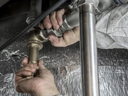 Pair of hands holding connecting water pipes together.